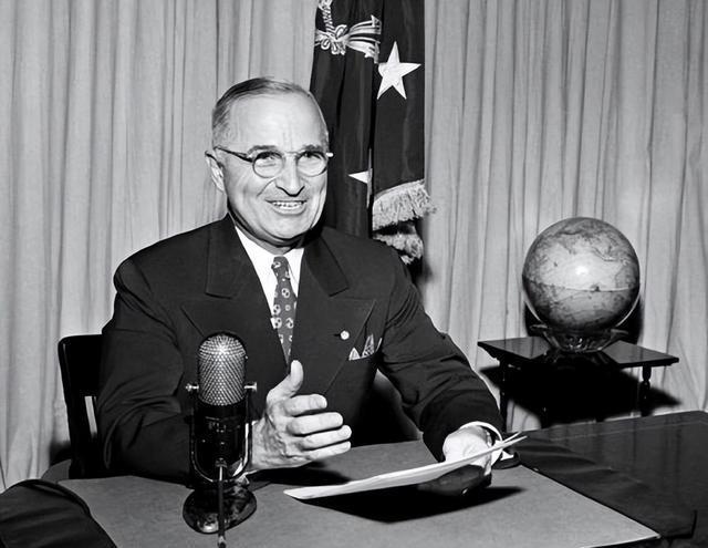 A person sitting at a desk with a microphone and a globe Description automatically generated