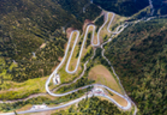 A winding road in a mountain Description automatically generated